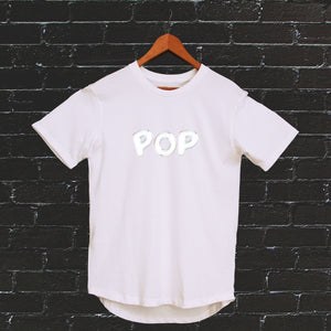 I'm With The Band® Bubble Pop T-shirt with iridescent print on white T on a coat hanger against a black painted brick wall