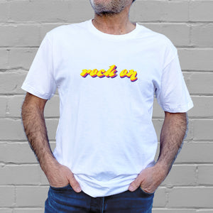 I'm With The Band® Rock On T-shirt with bright multi-colour print on white T being worn by a faceless man standing against a white painted brick wall
