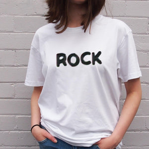 I'm With The Band® Bubble Rock T-shirt with black print on white T being worn by a faceless woman standing against a white painted brick wall