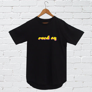 I'm With The Band® Rock On T-shirt with bright multi-colour print on black T on a coat hanger against a white painted brick wall
