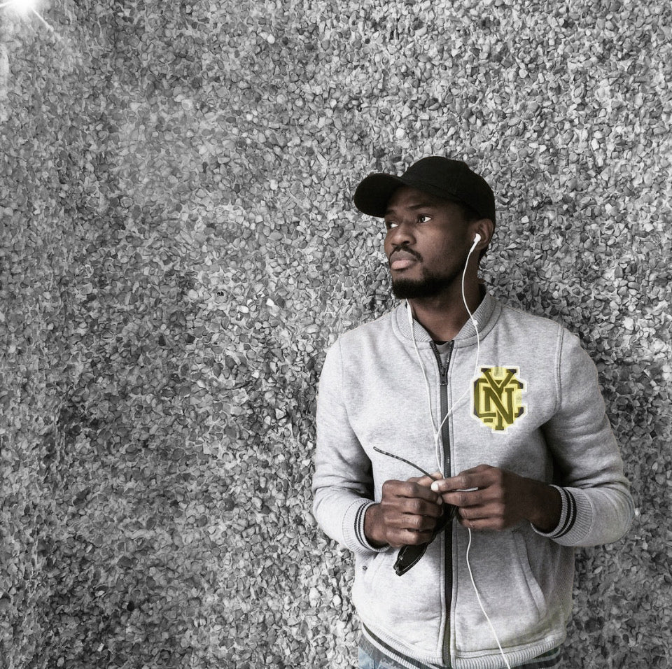 Tosin leans on a pebble-paved wall, relaxes to the music in his ear-pods and looks into the distance. 