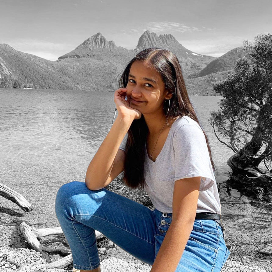 Portrait of Pragya, smiling at camera and with her elbow leaning on her knee