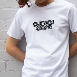 I'm With The Band® Funky Dory T-shirt with black print on white T being worn by a faceless young man standing against a white painted brick wall